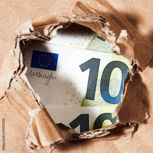 one hundred euro banknote through the hole in paper background