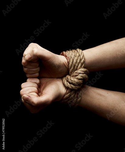 Hostage hands tied with a rope over black background