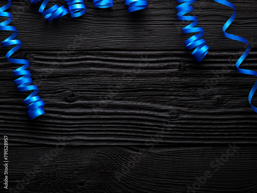 blue ribbon for celebration on a black wooden background