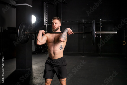 Strong man performing front squat, barbell resting on front shoulders. Routine workout for physical and mental health.