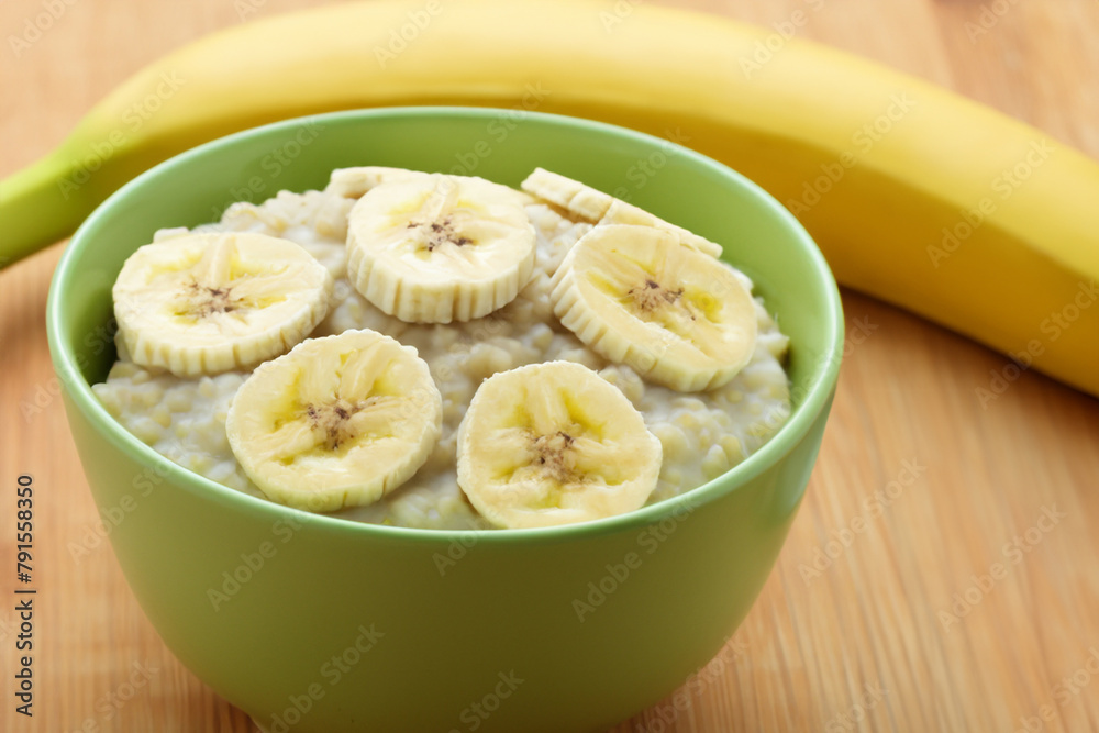 porridge with banana. on a wooden table there is a small green plate with milk porridge decorated with banana slices, close-up, useful concept porridge with banana. on a wooden table there is a small green plate with milk porridge decorated with banana slices, close-up, useful concept