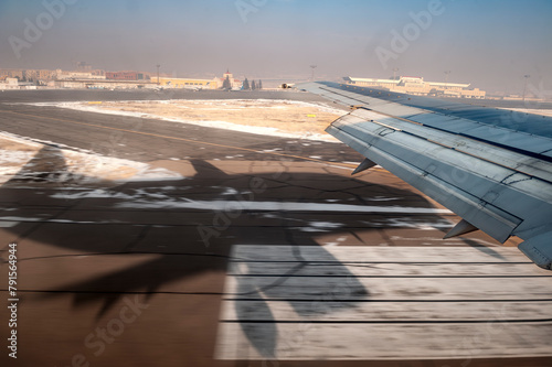 Landung oder Start eines Flugzeugs aus Sicht eines Passagiers mit Piste, Schatten des Flugzeugs und Häusern des Airports mit Bewegungsunschärfe