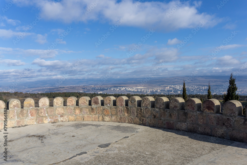 View of the mountains and the city of Rustavi from the tower of the Shavnabada monastery Beautiful cypress trees. Bright blue sky with clouds. Georgia.