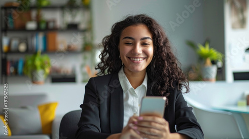 A woman in a business suit is smiling and holding a cell phone
