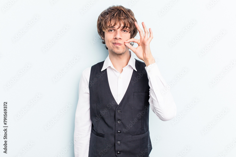 Young caucasian waitress man isolated on blue background with fingers on lips keeping a secret.