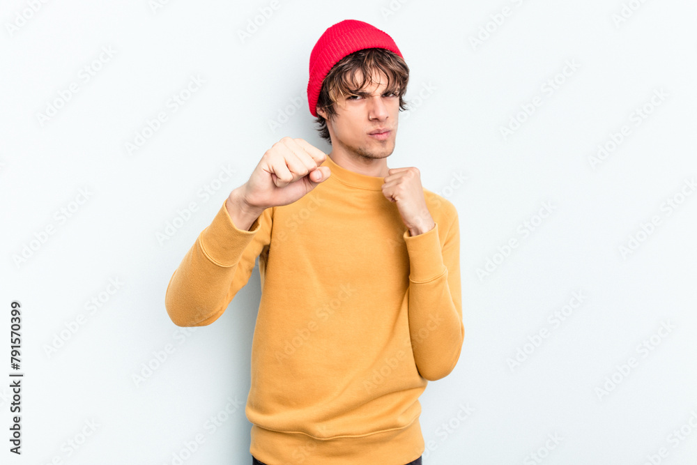 Young caucasian man isolated on blue background throwing a punch, anger, fighting due to an argument, boxing. Young caucasian man isolated on blue background throwing a punch, anger, fighting due to an argument, boxing.