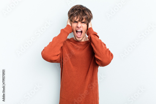 Young caucasian man isolated on blue background screaming, very excited, passionate, satisfied with something.