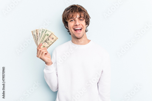 Young caucasian man holding banknotes isolated on blue background