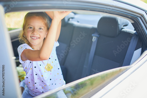 Young Girl Joyfully Waving Hand Out of Car Window on Sunny Day