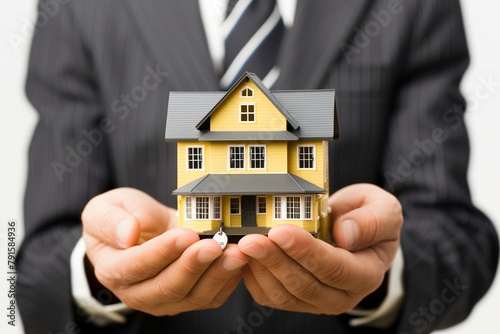 Businessman holding a miniature house in his hands