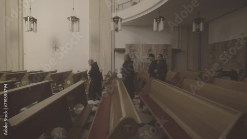 Christian priest in robes walking along church aisle side view tracking shot. Monks in catholic temple. Religious tradition and christianity concept photo