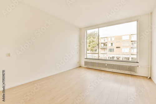 Bright empty room with large window and wooden floor photo
