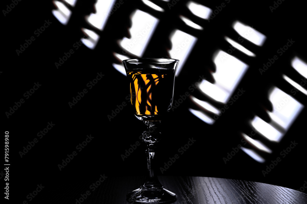 Jeden kryształowy kieliszek z jasnym drinkiem stoi na barze, nocna impreza - obrazy, fototapety, plakaty 
