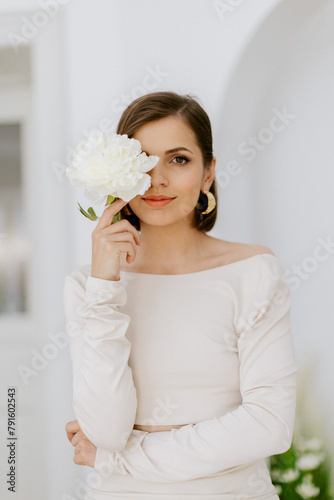 Elegant girl model with flower in studio with white wall