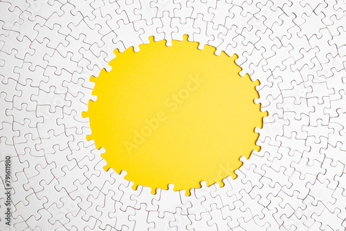 Plain white jigsaw puzzle  on yellow  color background, oval shaped frame, abstract backdrop