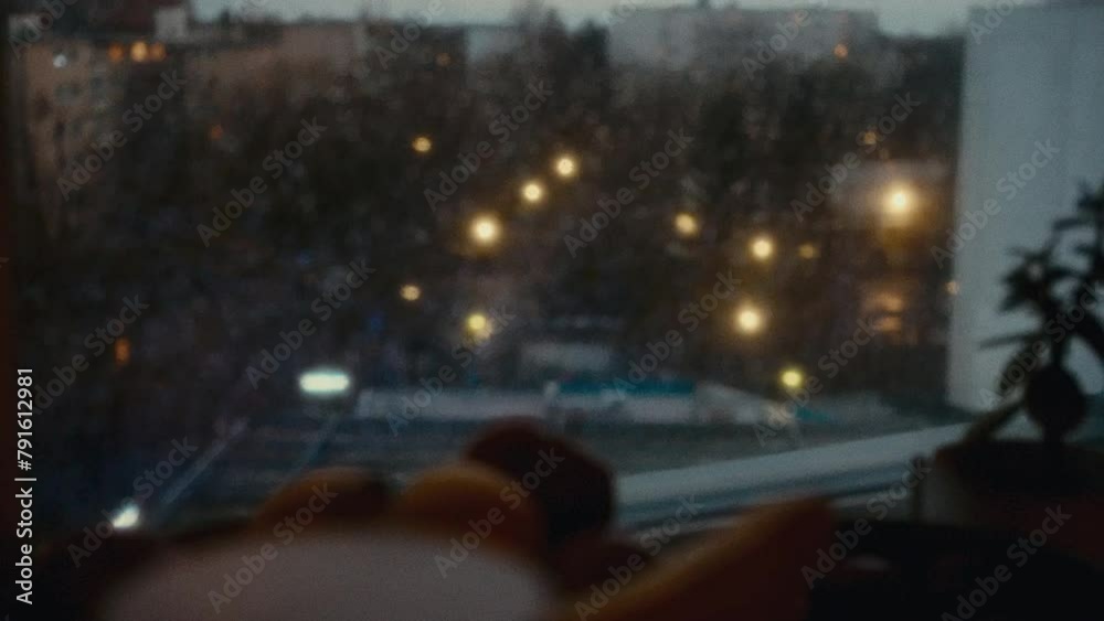 City being seen by someone in a window, the camera refocus on the drops of rain in the window and the bowl of fruit