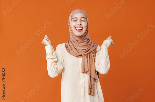beautiful young smiling muslim woman in traditional religious hijab rejoices in victory.