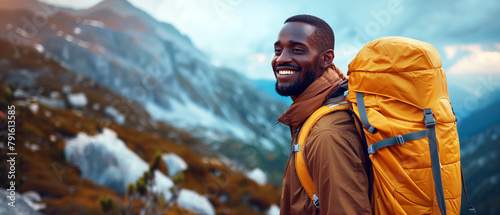 A handsome black man enjoys a summer vacation tour in the mountains wearing a brown hiking jacket and a mustard yellow backpack photo