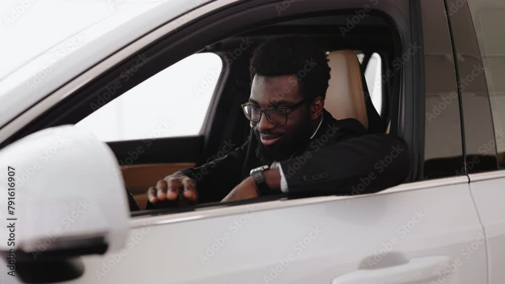 Calm African man, customer, buyer, client in suit holding hands on steering wheel choose auto want buy new automobile in car showroom vehicle salon dealership store motor show indoor. Sales concept. Calm African man, customer, buyer, client in suit holding hands on steering wheel choose auto want buy new automobile in car showroom vehicle salon dealership store motor show indoor. Sales concept.