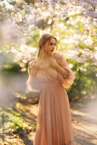 Beautiful  girl in pink  vintage dress  standing near colorful flowers. Art work of romantic woman .Pretty tenderness model posing with emotions.