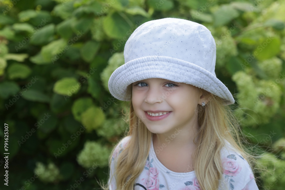 Candid outdoor portrait of happy little girl with bucket hat