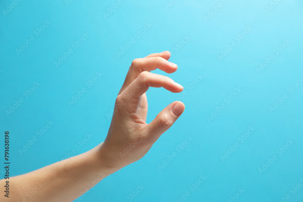 Woman holding something in hand on light blue background, closeup Woman holding something in hand on light blue background, closeup