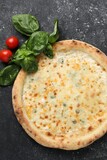 Delicious cheese pizza, basil and tomatoes on black textured table, flat lay
