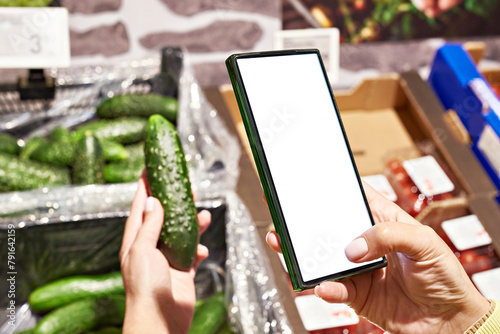 Cucumber vegetable in hand and smartphone isolated white © Sergey Ryzhov