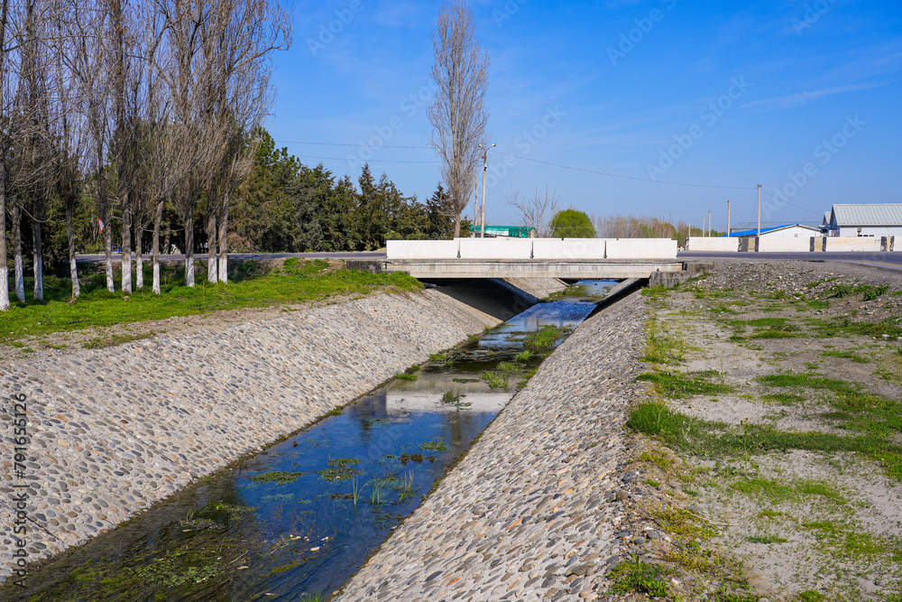 Water canal with stone embankments in Xo'ja Ismoil near Samarkand in Uzbekistan, Central Asia