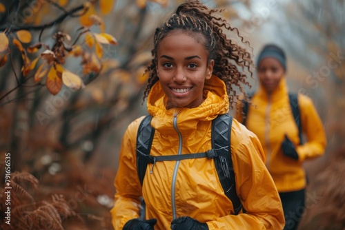 A cheerful woman hiker with a backpack in autumn scenery, with another hiker in the background photo