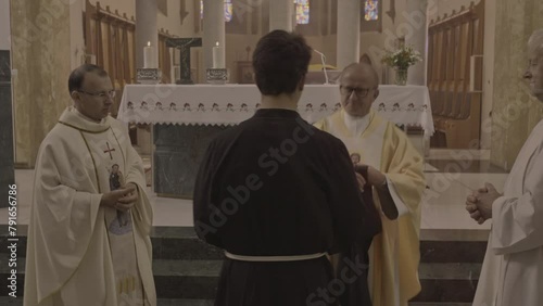 Monk ordination ceremony in christian church zoom out dolly shot. Ordinand and priests standing near sanctuary during religious ceremony. Consecration concept