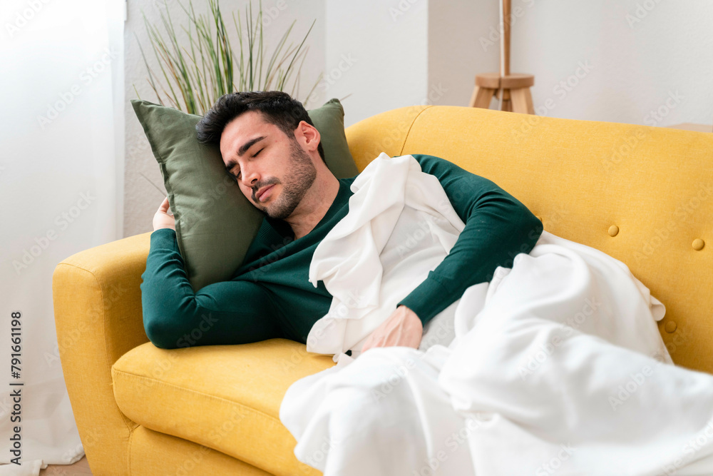 Man sleeping peacefully on a yellow sofa with a white blanket Man sleeping peacefully on a yellow sofa with a white blanket