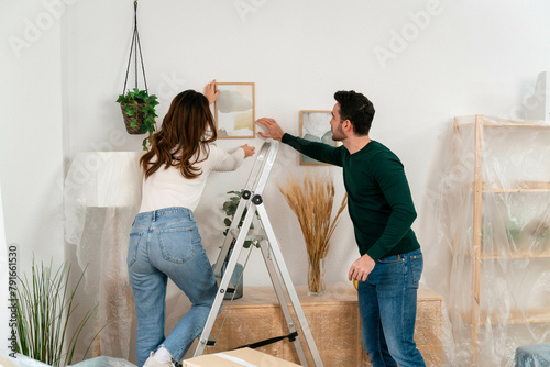 Couple arranging a picture frame on a wall photo