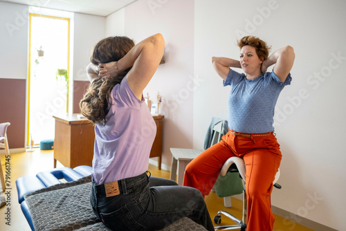 Woman stretching in a clinic with therapist assisting photo