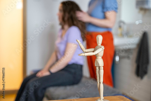 Wooden mannequin in focus with blurry hairstyling session in background photo