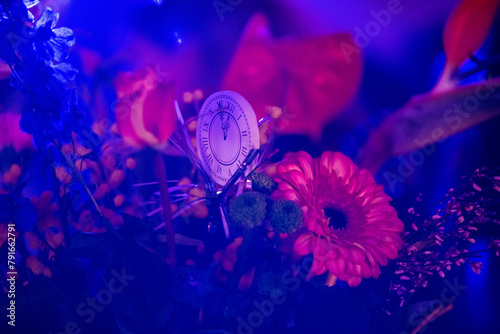 Hygrometer amidst vibrant flowers under blue lighting. photo