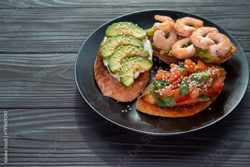 Bruschetta with avocado, shrimp, tomatoes, guacamole, cream cheese and herbs. Healthy eating.