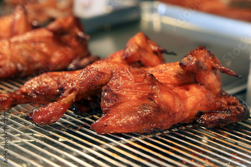 Grilling whole chickens in rotisserie machine, closeup. Grilled roasted whole Chicken. Black background. Top view. Copy space
