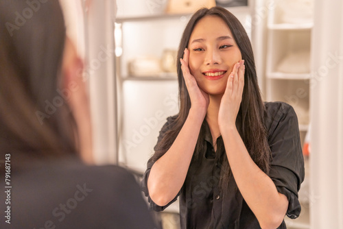 Smiling of beautiful asian woman fresh healthy white skin, clean, looking at mirror.asian girl touching on face applying cream, skincare, cosmetics, cosmetology, beauty, fashion at home.spa, wellness