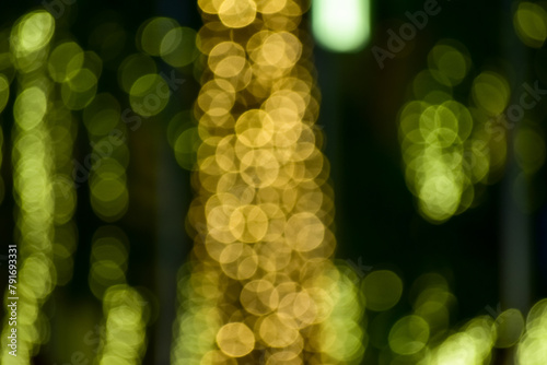 Abstract bokeh effect of the gold, yellow lights on black background. City street light decorations. Rows of LED gold colored light spots with black background. 