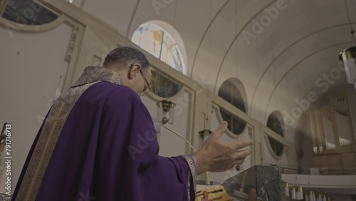 Christian priest in violet robe preaching in church back side view medium shot. Pastor standing on cathedral podium and talking. Christianity concept