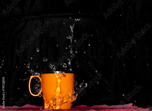 Splashing Water From Orange Color Cup
