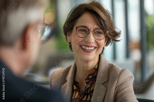 A businesswoman CEO wearing glasses engaged in a conversation with a man, conveying warmth and approachability