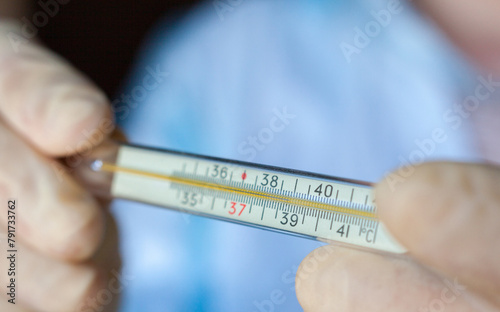 Hands holding medical thermometer.