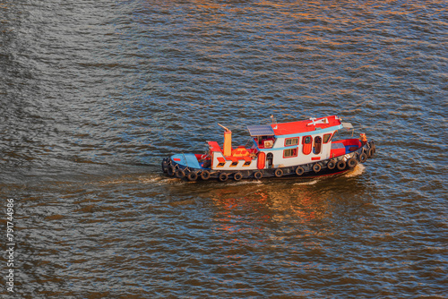 Moving small tug boat on the Chao Phraya River at Bangkok, Thailand. Tugboat ship is equipped with solar panels