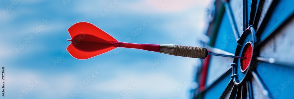 A perfect bullseye with a red dart firmly stuck in the center of a dartboard, symbolizing accuracy and goal achievement