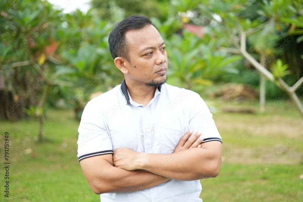 Asian male model wearing white shirt is sitting with facial expression in nature Asian male model wearing white shirt is sitting with facial expression in nature