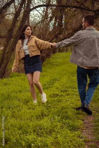 A boy and a girl hold hands, spin, and dance in the forest, teenage romantic relationship and friendship Valentine's Day