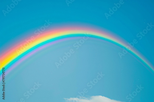 A vibrant rainbow stretching across the clear blue sky, adding a touch of magic to a summer day isolated on solid white background.