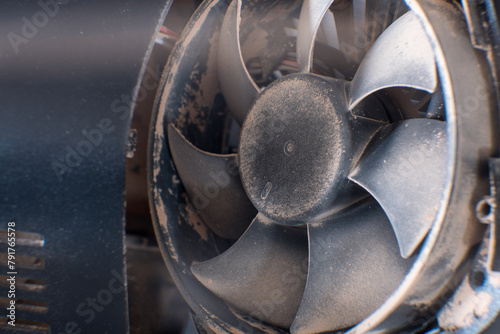 A detailed shot of a grimy metal computer fan resting on a clean white tabletop, reminiscent of automotive tire components like alloy wheels, rims, and hubcaps © Aleksandrs